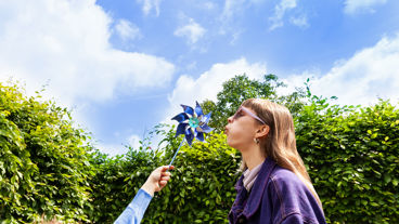Vrouw blaast tegen een papieren windmolentje