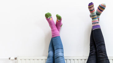Inzoom op twee paar benen tegen een radiator
