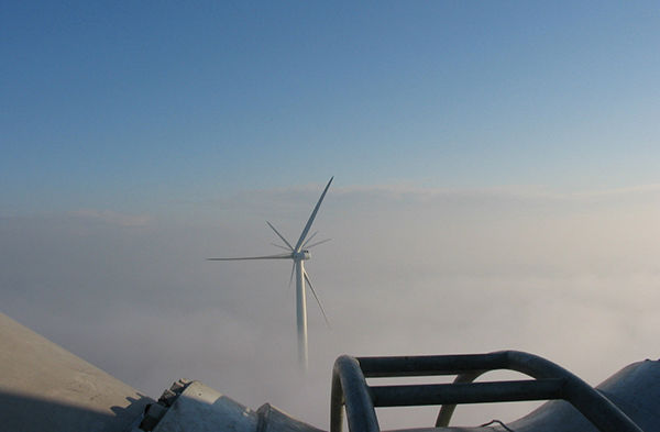 Afbeelding van een windturbine boven een wolkendek