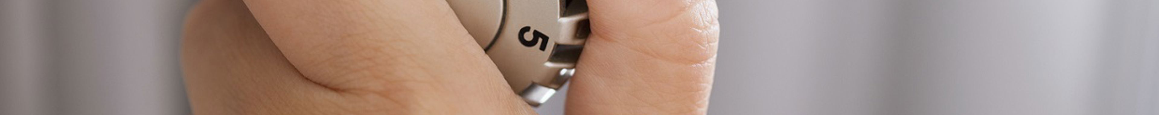 Inzoom van een hand die een radiatorknop bedient